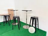 plusieurs tabourets et tables dans une pièce recouverte d'une moquette verte