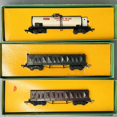 trois petits trains sont rangés dans des boîtes posées sur une surface jaune
