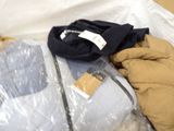 a bag of clothing sitting on the floor next to a pair of gloves