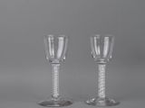pair of clear wine glasses with silver rims on a grey background