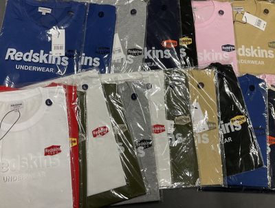 a lot of t - shirts wrapped in plastic on a table