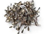 un tas de cuillères et de fourchettes en argent posées sur une surface blanche
