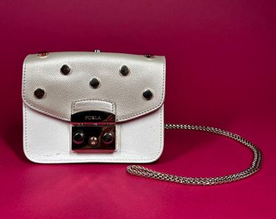 a close up of a white purse on a pink background