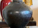 a black vase sitting on top of a glass table next to a lamp
