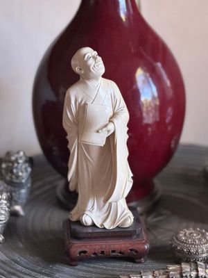 a statue of a man on a table next to a red vase
