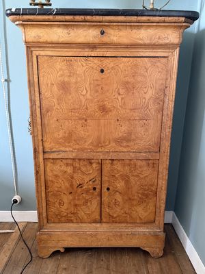 une armoire en bois placée dans un coin de la pièce, sur laquelle est posée une lampe