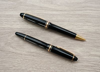 two pens sitting on top of a wooden table next to each other