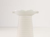 a white vase sitting on top of a white table next to a white wall