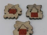 three small wooden sheep with tags on them sitting on a white surface