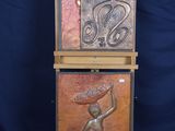 two wooden sculptures of a woman holding a basket on top of a wooden stand