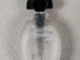 a small bottle with a brush inside of it on a white surface