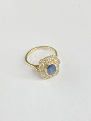 gros plan d'une bague en or avec une pierre bleue