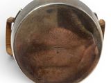 a silver pot on a wooden stand on a white surface