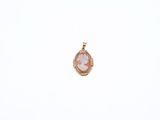 a pink and gold pendant with a picture of a woman in a dress