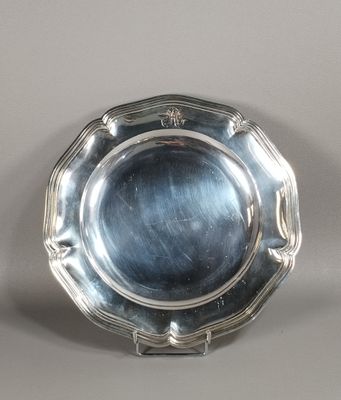 un plat ancien en argent posé sur un socle, sur une surface grise