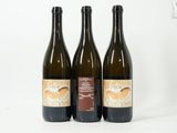 trois bouteilles de vin posées les unes à côté des autres sur une surface blanche