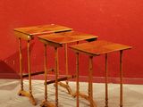 trois tables en bois posées sur un sol en béton, près d'un mur rouge