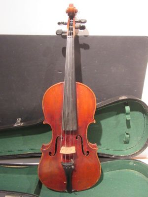 un vieux violon repose dans son étui, posé sur une table
