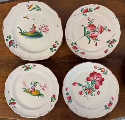 four plates with birds and flowers painted on them on a wooden table