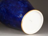 a blue vase with a gold rim sitting on a table
