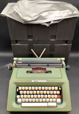 une vieille machine à écrire posée sur une table, à côté d'une boîte