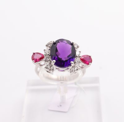 a close up of a ring with a purple stone surrounded by pink and white stones