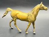 a gold horse that is walking on a black surface