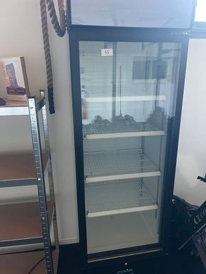 une photo d'un réfrigérateur à porte vitrée dans un coin d'une pièce