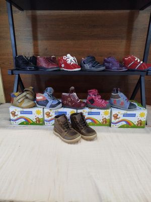 several pairs of children ' s shoes are lined up on a shelf