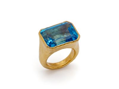 Gros plan sur une bague en or ornée d'une topaze bleue