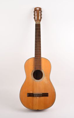 une image représentant une petite guitare posée sur une surface blanche