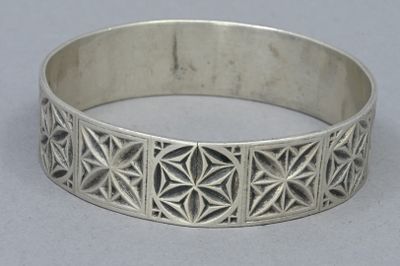 a close up of a silver bracelet with geometric designs on it