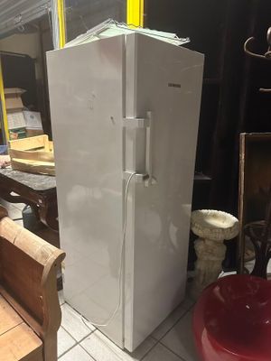 a white refrigerator sitting in a room next to a bench