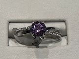 une photo d'une bague en diamant violette dans un écrin blanc