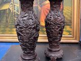 deux vases posés sur une table devant un tableau