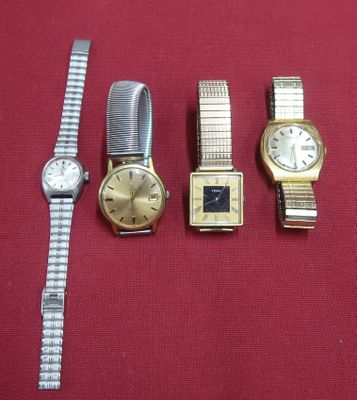 trois montres et un bracelet de montre posés sur un tissu rouge