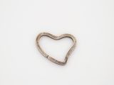 a close up of a metal heart shaped object on a white surface