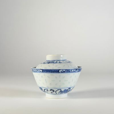bol en porcelaine bleue et blanche avec couvercle, posé sur un fond blanc
