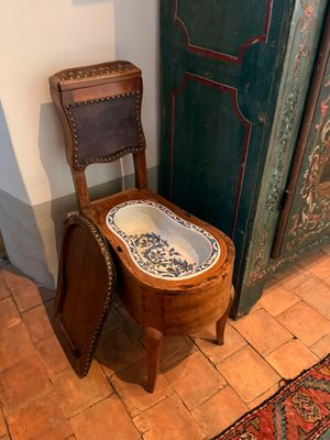 des toilettes avec un siège en bois, à côté d'une porte verte