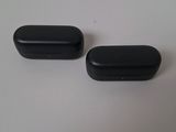 two black plastic pill caps sitting on top of a white table