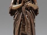 statue en bronze représentant une femme tenant un bébé dans ses bras, posée sur un socle en bois