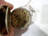 une personne tenant une montre de poche attachée à une chaîne
