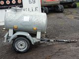 a trailer with a tank attached to it in front of a building