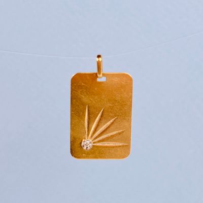 un pendentif en or orné d'un diamant, suspendu à un cordon