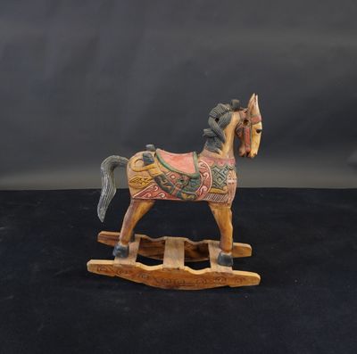 cheval à bascule en bois sculpté sur fond noir avec un fond gris