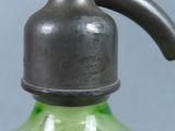 a green glass bottle with a black handle on a gray background