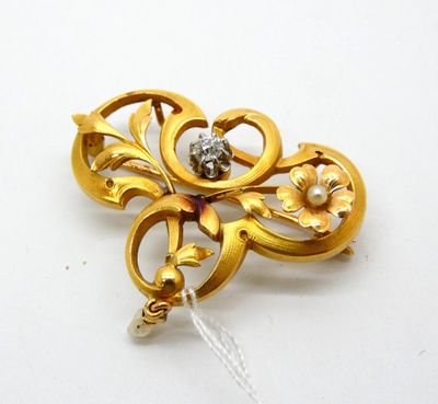 a gold brooch with a pearl in the center