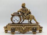 une statue d'un homme assis au sommet d'une horloge
