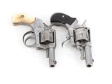 pair of old revolvers on a white surface with a wooden handle