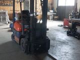 un chariot élévateur dans un entrepôt où il y a beaucoup de bois